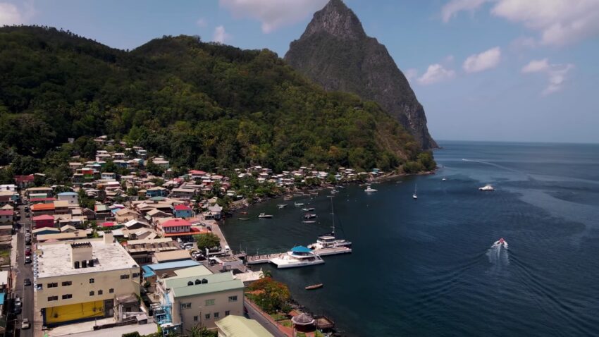 Boats sit near a coastal town under the Pitons in St. Lucia