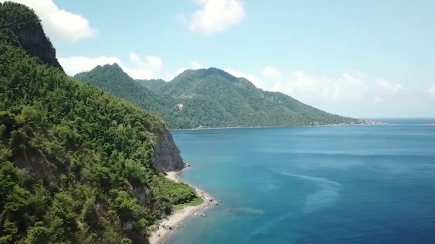 Dominica’s green cliffs and mountain coastline beside calm blue Caribbean water