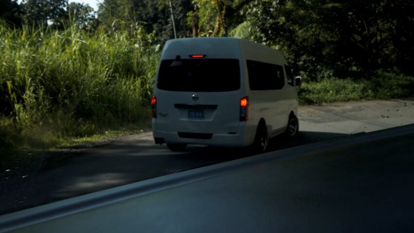 A white tour van drives along a narrow rural road in St. Lucia