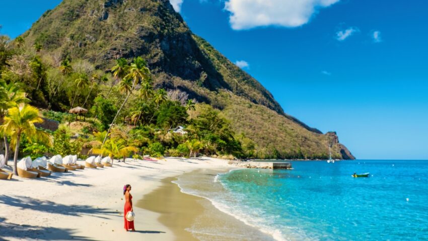 A woman stands on a St. Lucia beach below the Pitons