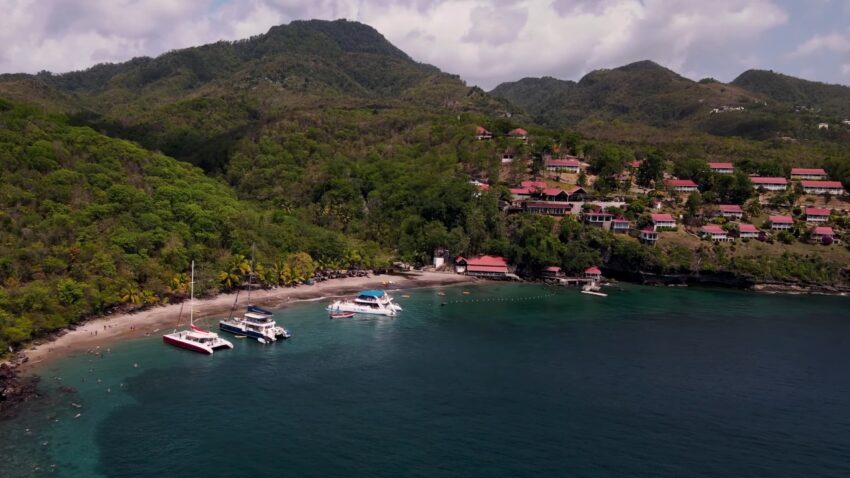 Boats anchor near a small St. Lucia beach below green hills