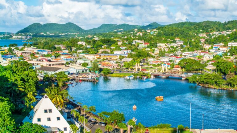 A coastal town in St. Lucia sits beside a blue bay with lush hills beyond