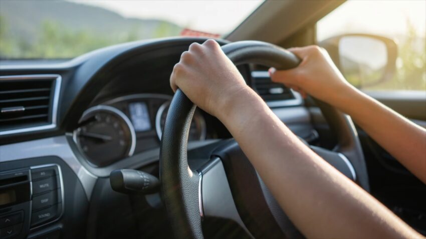 A rental car driver holds the wheel on a sunny St. Lucia road