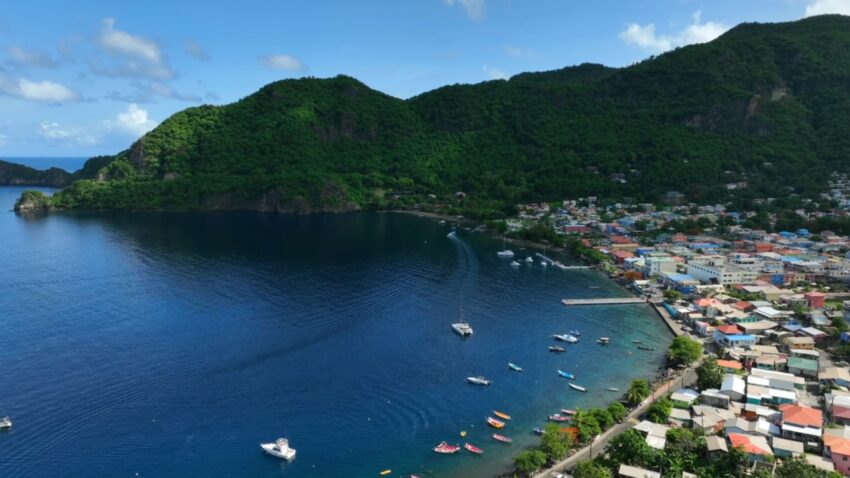 An aerial view shows a coastal town on Saint Lucia beside green hills and blue water
