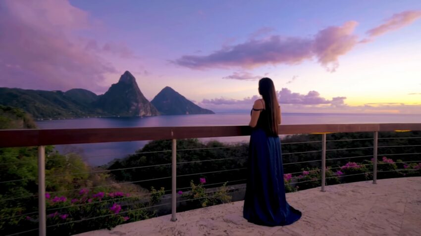 A woman views the Pitons and sea at sunset in St. Lucia
