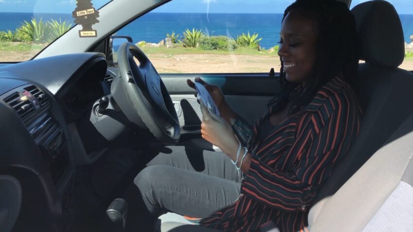 A woman smiles in a parked car by the St. Lucia coast