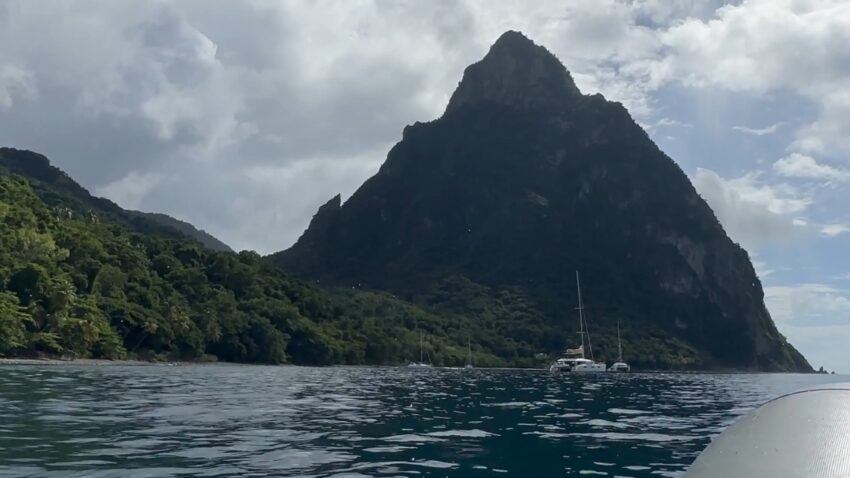 Sailboats sit near a Piton on the coast of St. Lucia