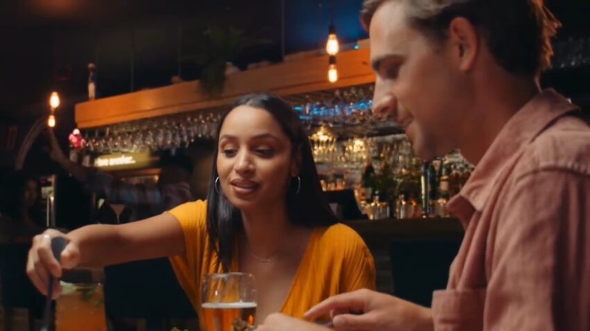 A couple shares drinks at a lively Caribbean bar at night